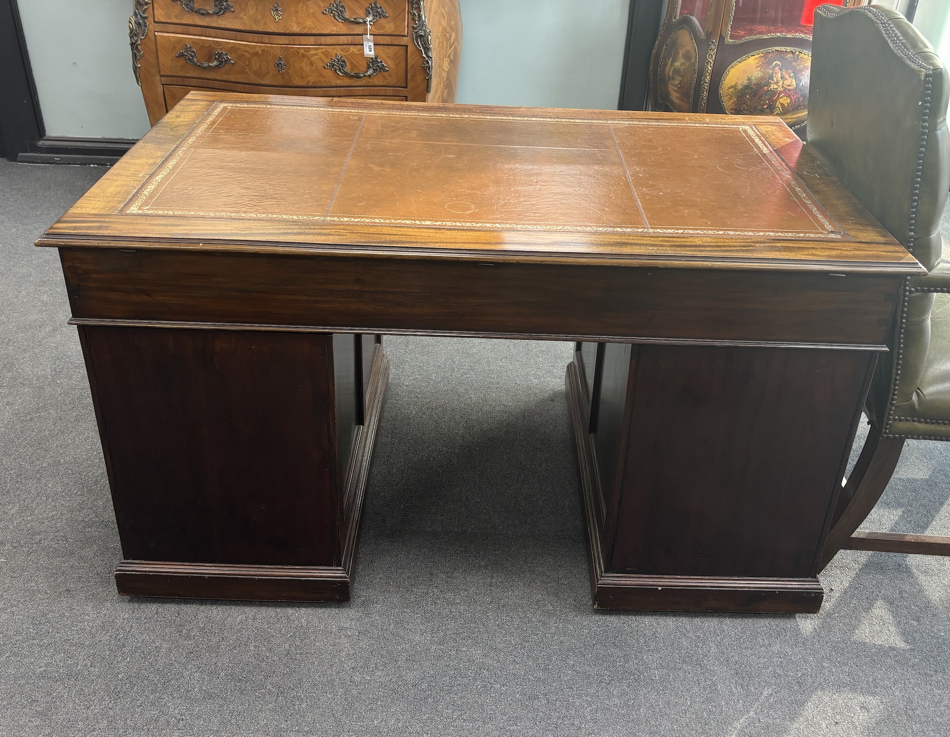 A George III style mahogany pedestal desk, width 138cm, depth 83cm, height 77cm together with a Gainsborough style buttoned green leather elbow chair